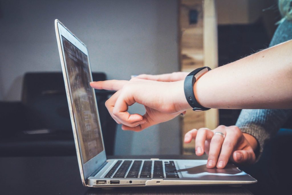 A sideview shot close up of two hands pointing at a laptop screen
