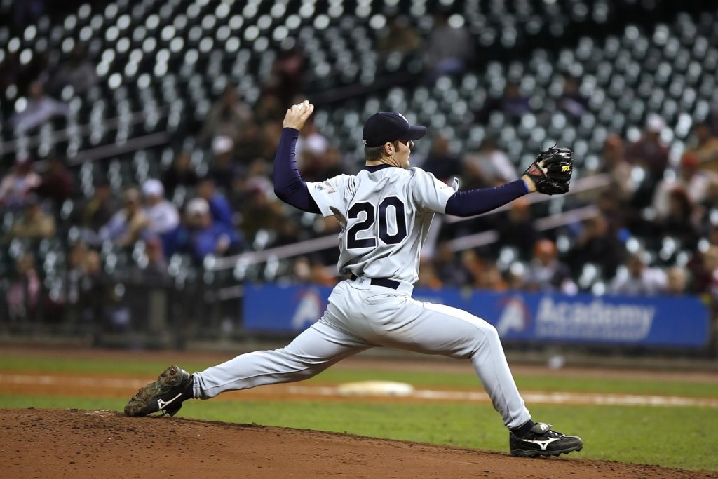 Baseball pitcher mid pitch in a grey uniform with the number 20
