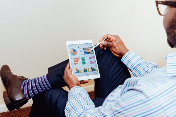 Man in looking at bar, circle, and line graphs with a stylus on a tablet