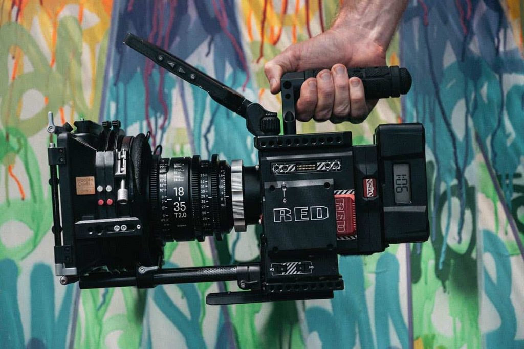 Sideview of a film camera in front of a white wall with paint letters