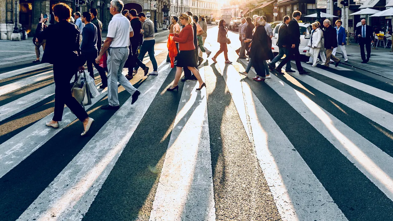 Sideview of a street crossing with many people crossing