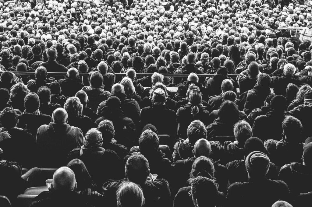 black and white image of the backs of many people sitting