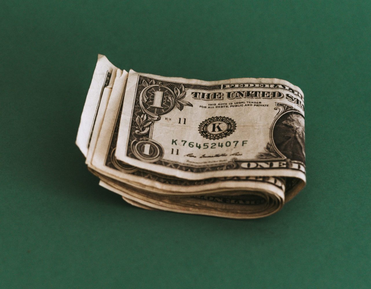 Smile pile of one dollar bills folded in half on a green background