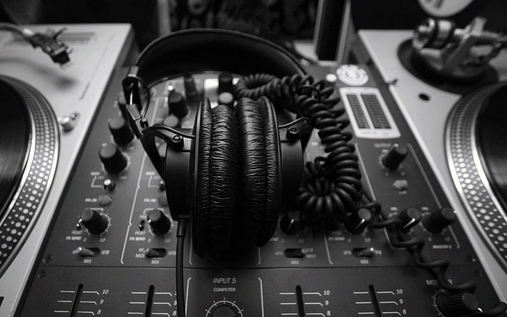 Black and white image of headphones laying in the middle of an audio mixing station