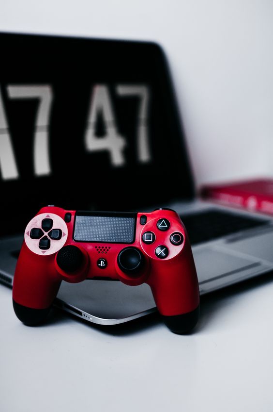 Red game controller standing up against a laptop