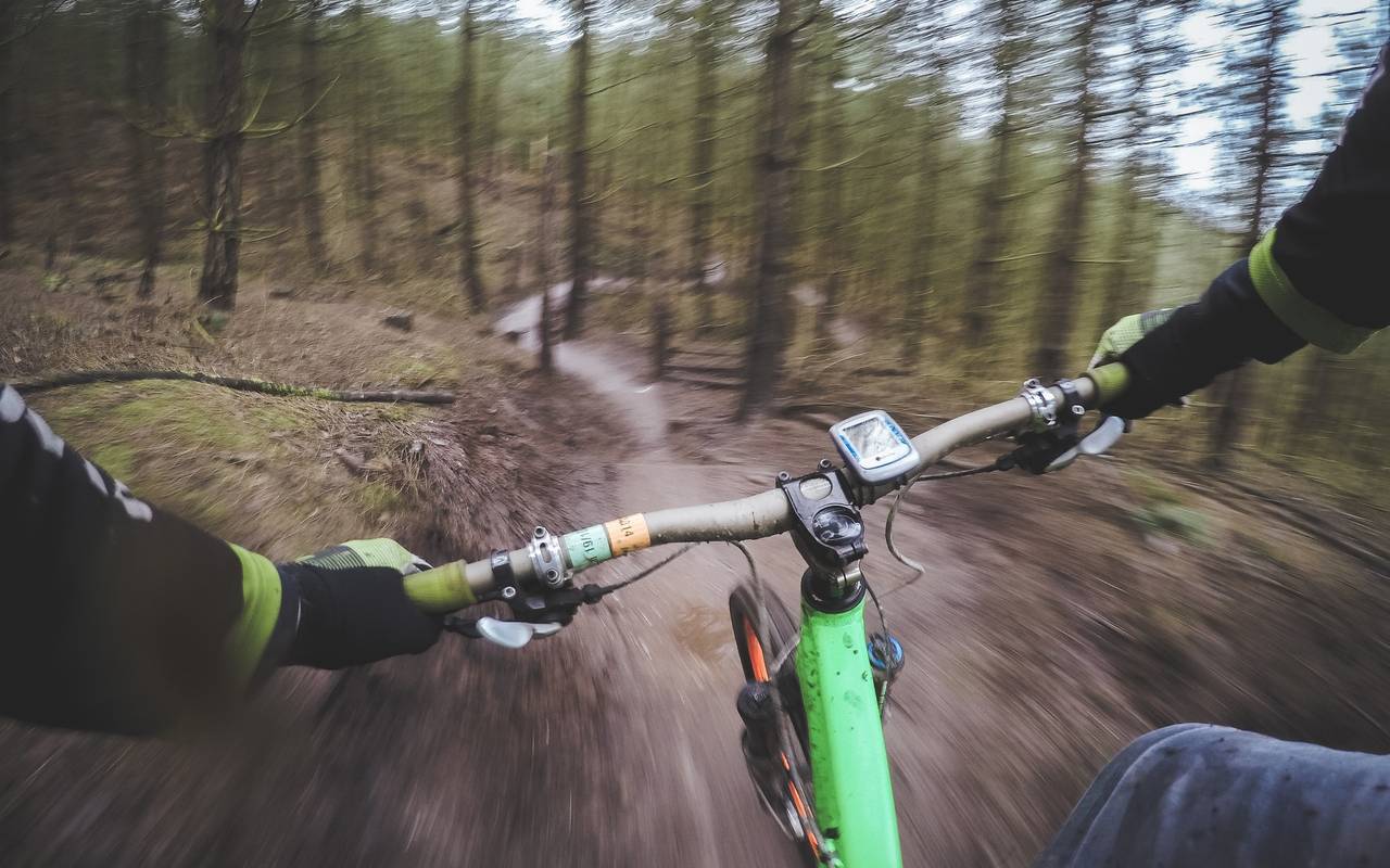 POV perspective from a biker going down a dirt train in the woods quickly