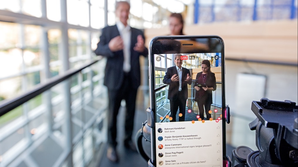 man and women being recorded by a smartphone during a Facebook live