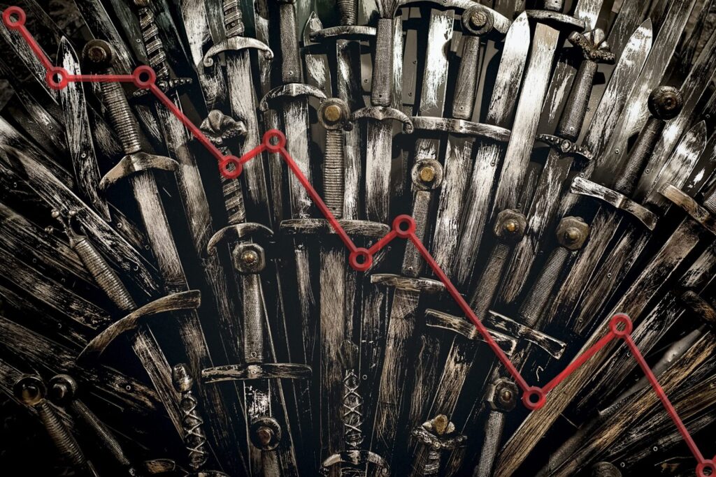 Close-up of man gray and worn swords stacked on each other vertically with a red line graph trending down on top