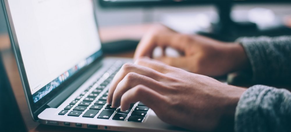 Hands typing on a laptop keyboard