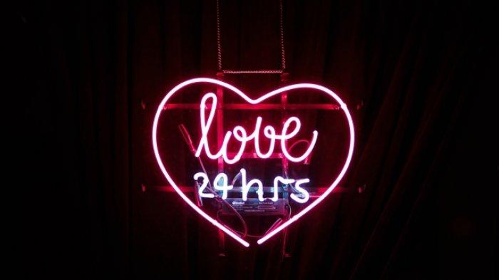 The text "love 24 hrs" made by a pink heart neon sign with the neon text in the center illuminating a black wall
