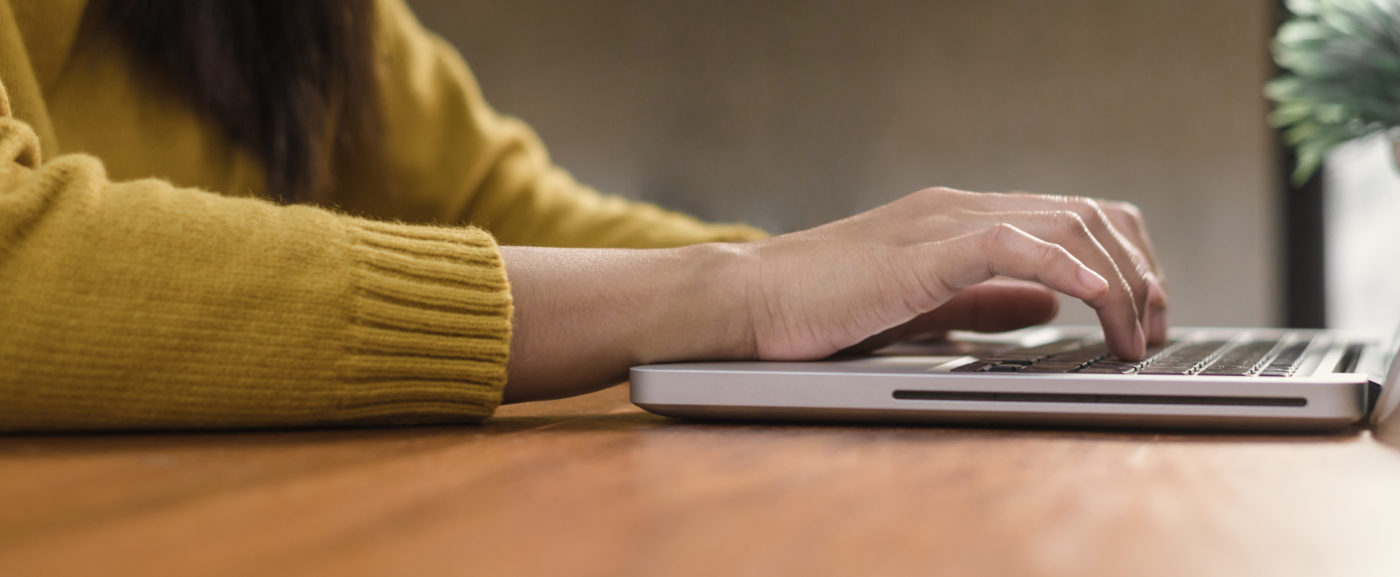 Young woman working with the laptop on a desk in coffee shop. Young woman working on weekend with her laptop in a warm sunlight day. Laptop working in the coffee shop concept. Panoramic banner.