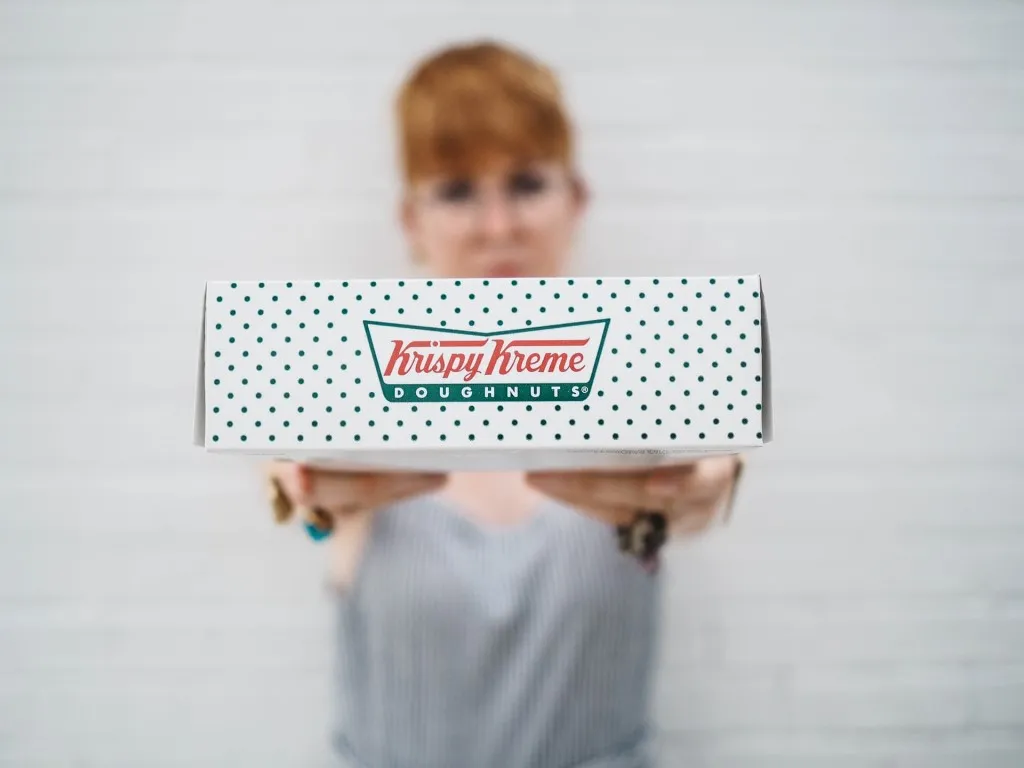 Krispy Kreme doughnuts box being held by a red haired women