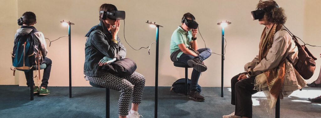 4 people sitting at 4 different virtual reality stations wearing virtual reality headsets