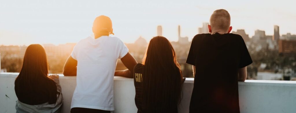 4 teenagers pictured from behind as they look over a wall at the city
