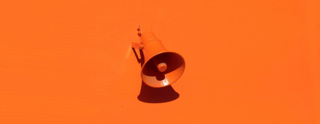 Orange megaphone laying on a orange background