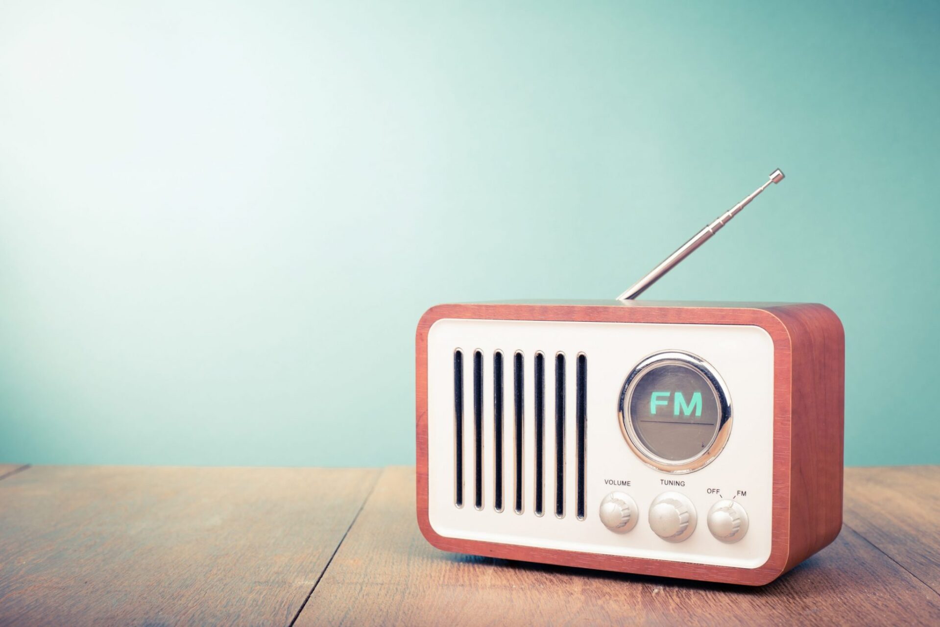 Old FM radio on a wood table in front of a green wall