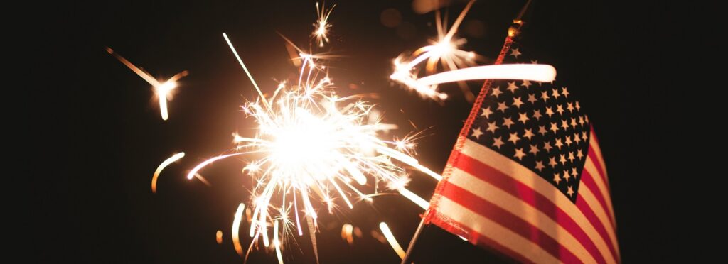 Sparkler and small American flag on a black background