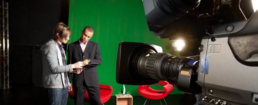 Man actor and women director pointing at clipboard in a set with a camera in frame