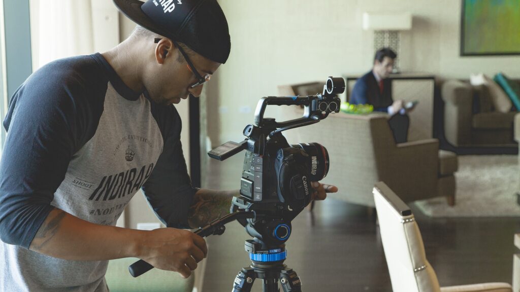 Man in a backward hat and long sleeve t-shirt with glasses operating a cannon film camera