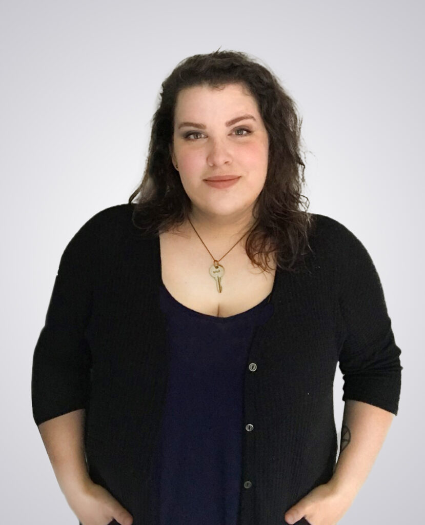 Professional headshot of a woman with brown hair wearing a black sweater on a white background