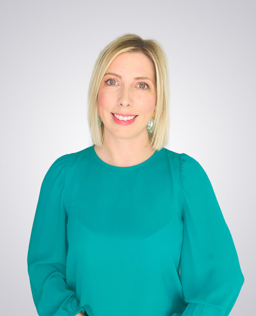 Professional headshot of a blonde women smiling wearing a green shirt