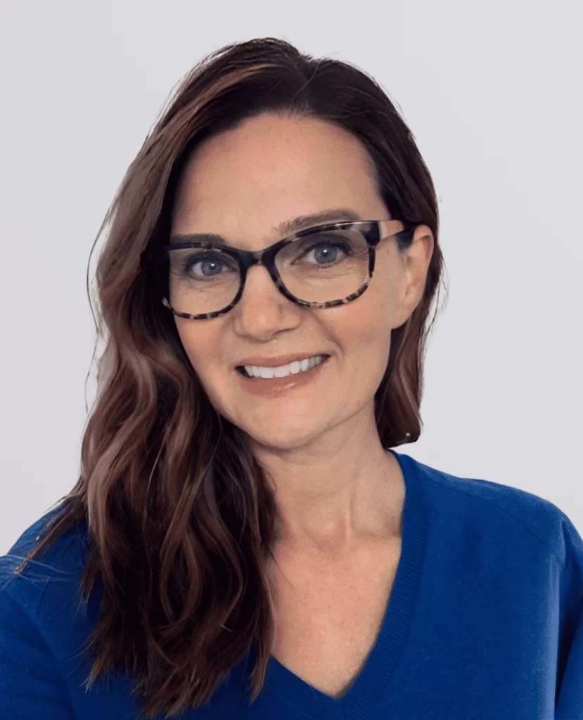 Professional headshot of a smiling women with glasses in a blue sweater