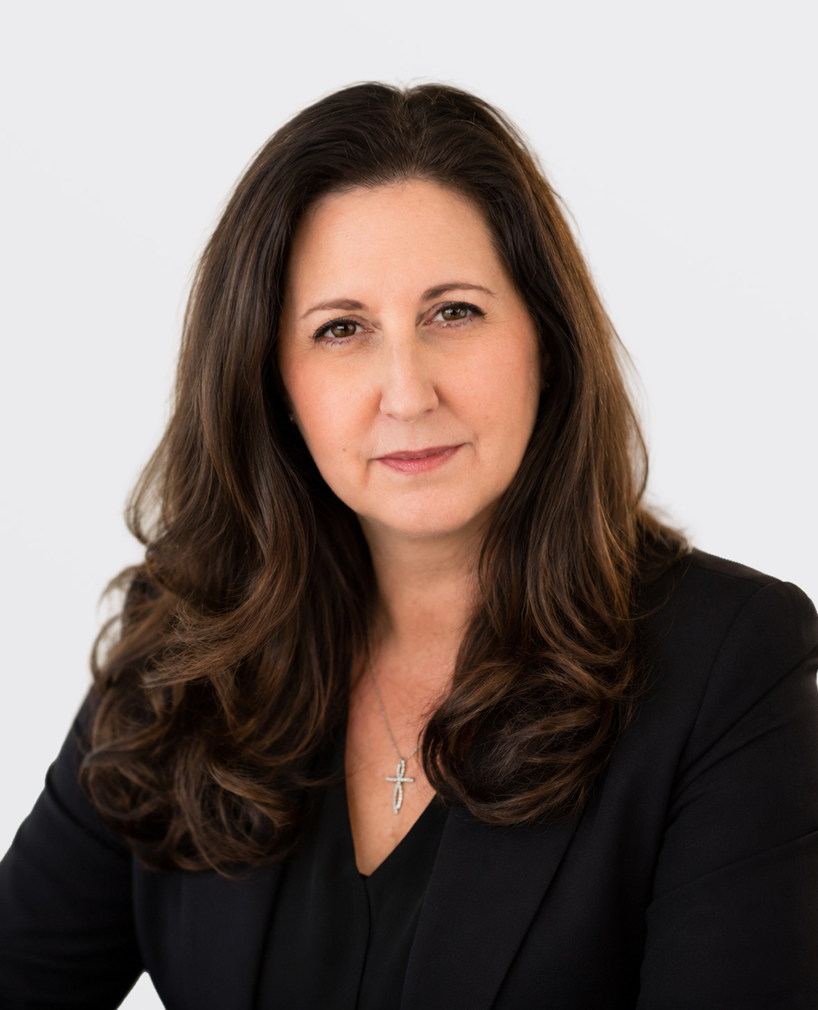 Professional headshot of a smiling brunette woman in a black suit jacket