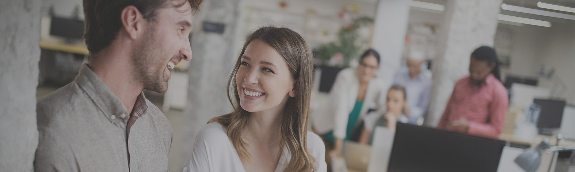Coworkers smiling in front of computer