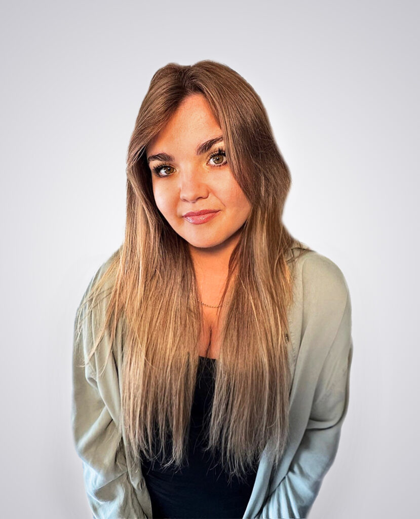 Professional headshot of a blonde woman smiling wearing a black shirt on a white background
