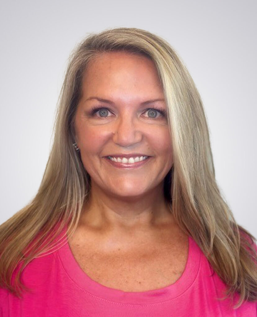 Professional headshot of a blonde women smiling in a pink shirt