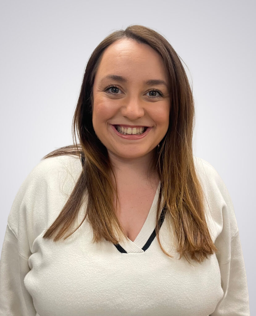 Professional Headshot of women with brown hair smiling wearing a white sweater on a white background