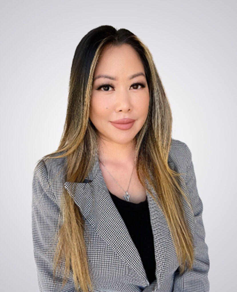 Professional headshot of a women with black and blonde hair in a striped black and white blazer on a white background