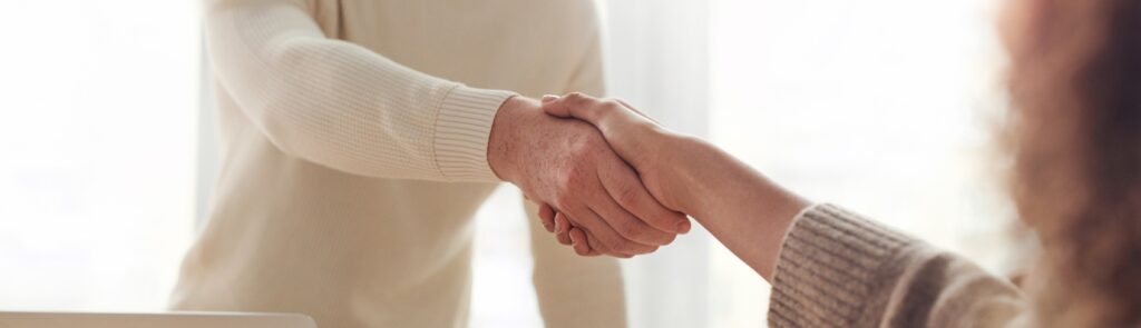Close-up image of people shaking hands in a casual setting