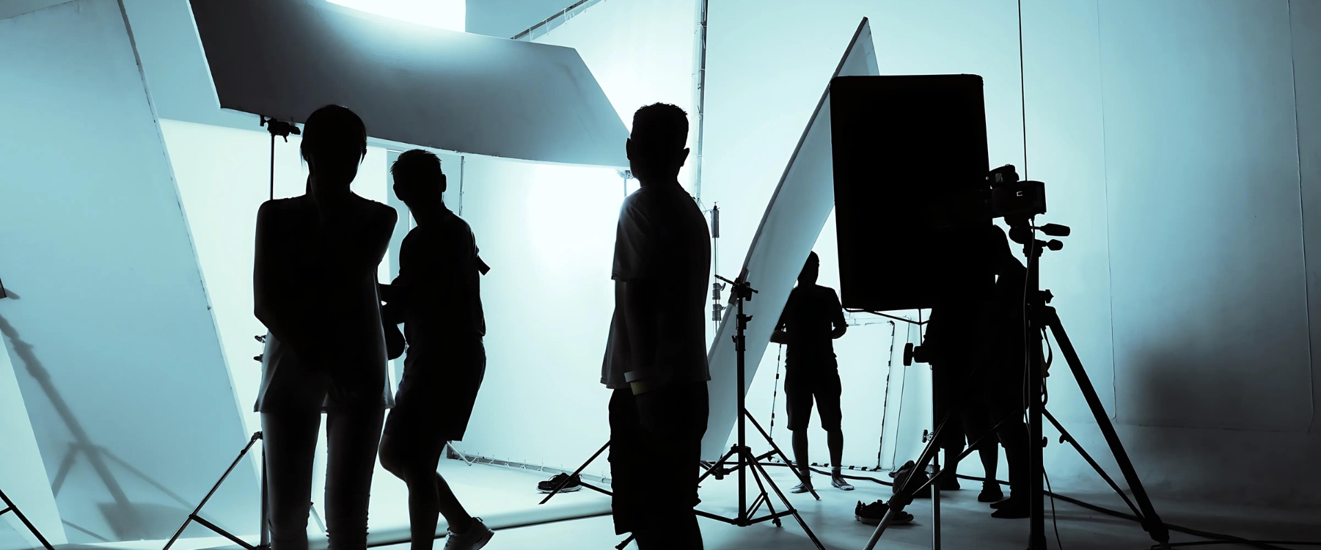 Video production crew setting up lights and equipment on a white set