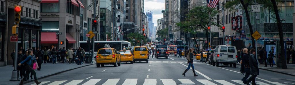 Busy city crosswalk with people and cars