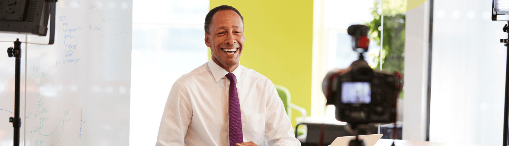 Smiling middle aged business mans smiling while being filmed making a corporate video