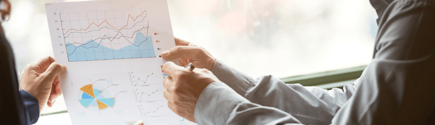 Two people pointing at charts on a piece of paper
